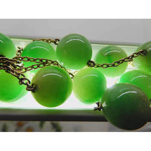 762 - A STRING OF CHINESE GREEN HARDSTONE BEADSlinked with yellow metal chains. each bead is 13.4mm, lengt... 