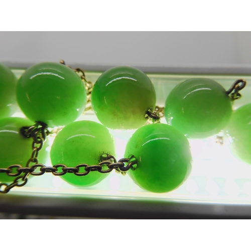 762 - A STRING OF CHINESE GREEN HARDSTONE BEADSlinked with yellow metal chains. each bead is 13.4mm, lengt... 