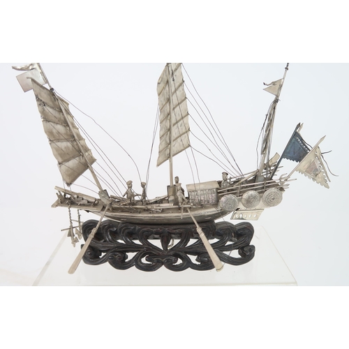 316A - A WHITE SILVER MODEL OF A JUNK mounted on a carved wood wave base, 20cm high, 22cm wide and 4cm... 