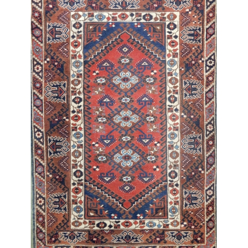 92 - A rust ground Balouch rug with three medallions, dark blue spandrels and a geometric border, 185cm l... 