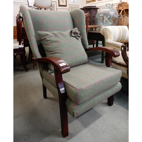 96 - A 20th century stained oak wingback armchair and footstool both upholstered in a wool tweed style fa... 