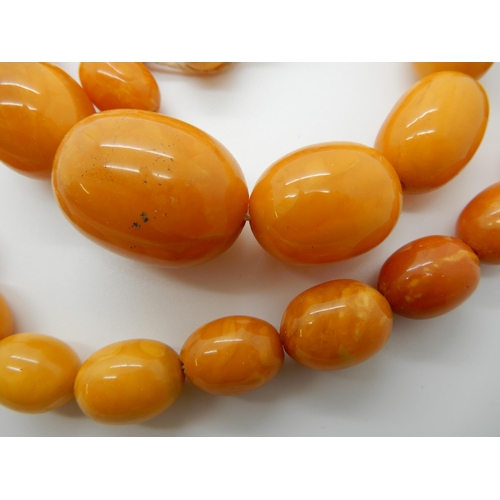 684 - TWO STRINGS OF AMBER COLOURED BEADS