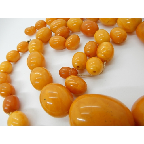 684 - TWO STRINGS OF AMBER COLOURED BEADS