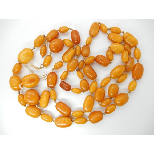 687 - A LONG STRING OF AMBER COLOURED BEADS (AF)