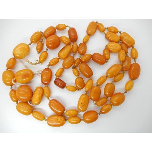 687 - A LONG STRING OF AMBER COLOURED BEADS (AF)