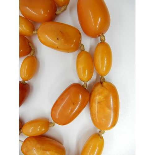 687 - A LONG STRING OF AMBER COLOURED BEADS (AF)