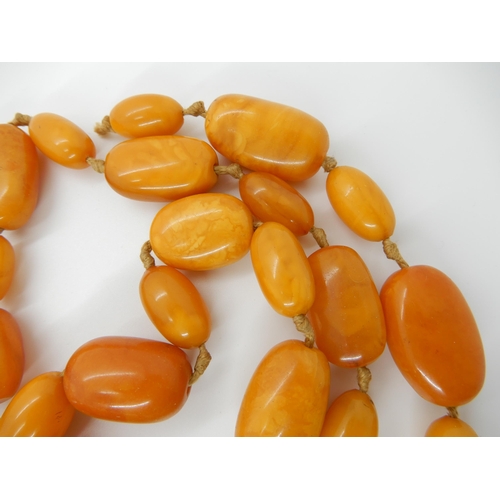 687 - A LONG STRING OF AMBER COLOURED BEADS (AF)