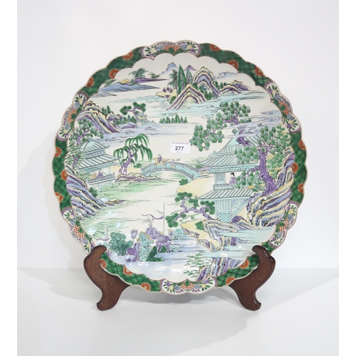 277 - A large Japanese charger with scalloped edge, painted in shades of green, purple and yellow on a whi... 