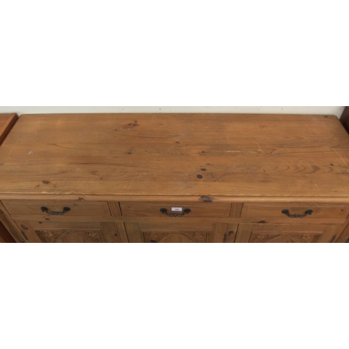 100 - A 20th century pine sideboard with three drawers over three gothic style carved panel cabinet doors,... 