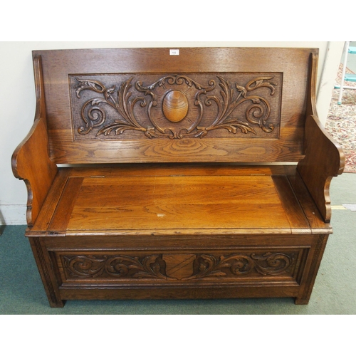 102 - An early 20th century oak monks bench/settle with carved back over hinged seat on base carved with f... 