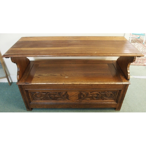 102 - An early 20th century oak monks bench/settle with carved back over hinged seat on base carved with f... 