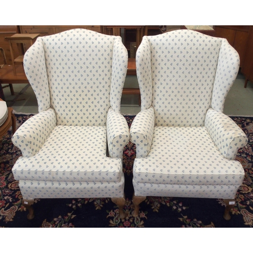 110 - A pair of 20th century wing back armchairs with white patterned upholstery on cabriole supports (2)