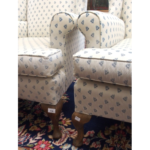 110 - A pair of 20th century wing back armchairs with white patterned upholstery on cabriole supports (2)