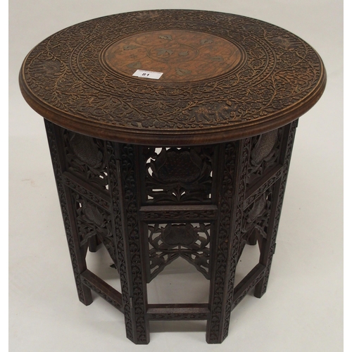 81 - A 20th century Moorish style circular top table with folding octagonal base carved with floral folia... 