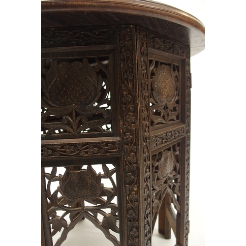 81 - A 20th century Moorish style circular top table with folding octagonal base carved with floral folia... 