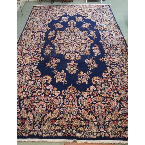 85 - A dark blue ground eastern style wool rug with floral foliate central medallion and borders, 501cm l... 