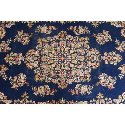 85 - A dark blue ground eastern style wool rug with floral foliate central medallion and borders, 501cm l... 