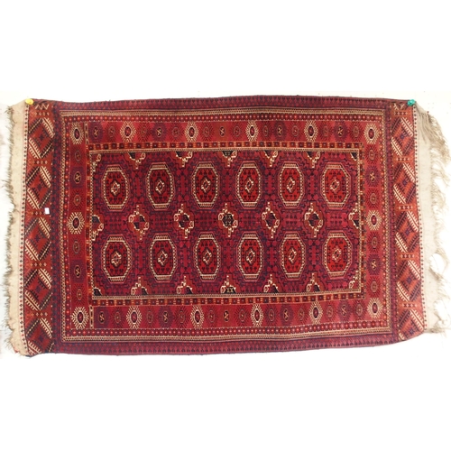 105 - A red ground Bokhara rug with all over medallion design and geometric borders