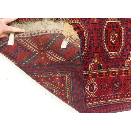 105 - A red ground Bokhara rug with all over medallion design and geometric borders