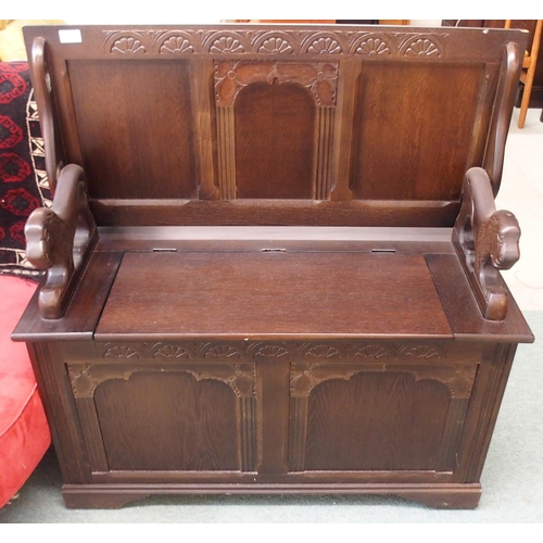 131 - A 20th century mahogany monks bench/settle with carved lion arms