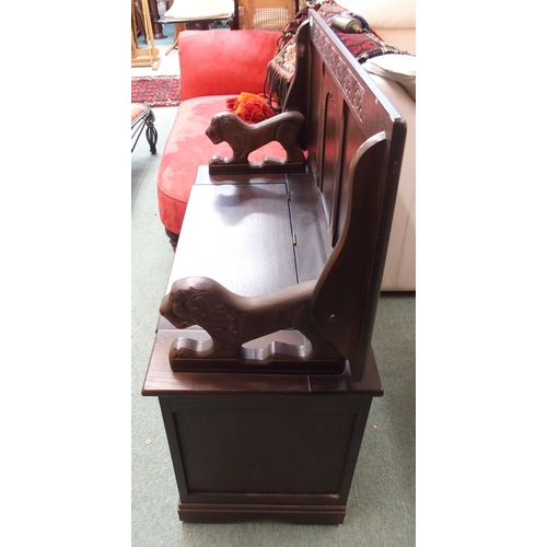 131 - A 20th century mahogany monks bench/settle with carved lion arms