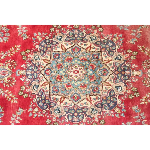 147 - A red ground Tabriz rug with blue and white floral central medallion, matching spandrels and a blue ... 