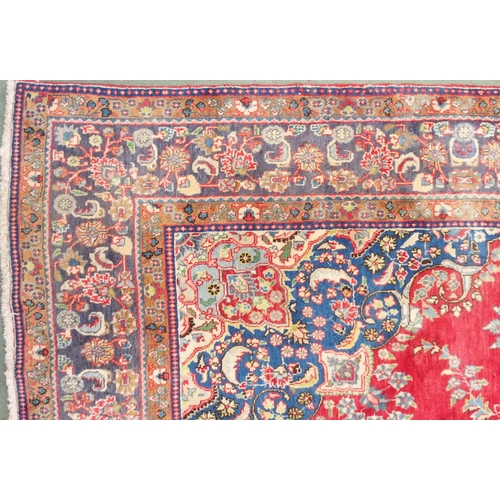 147 - A red ground Tabriz rug with blue and white floral central medallion, matching spandrels and a blue ... 