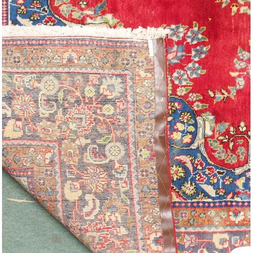 147 - A red ground Tabriz rug with blue and white floral central medallion, matching spandrels and a blue ... 