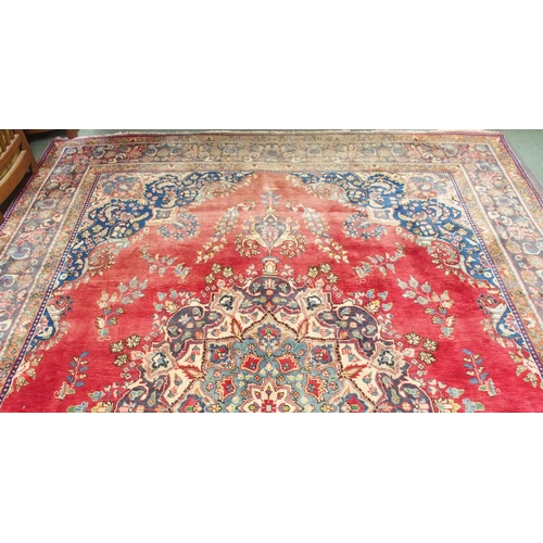 147 - A red ground Tabriz rug with blue and white floral central medallion, matching spandrels and a blue ... 