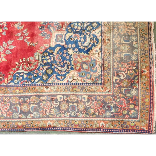 147 - A red ground Tabriz rug with blue and white floral central medallion, matching spandrels and a blue ... 