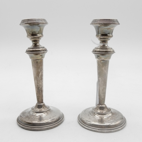 327 - A matched pair of silver candlesticks, of tapering cylindrical form, on a stepped circular base with... 