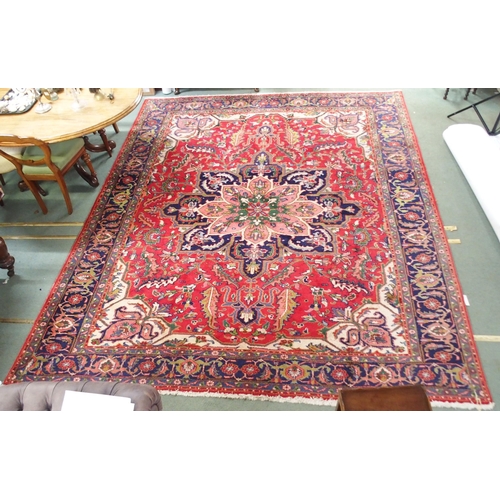 64 - A red ground Tabriz rug with multicoloured central medallion, matching spandrels and dark blue borde... 