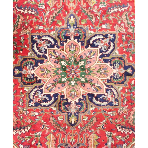 64 - A red ground Tabriz rug with multicoloured central medallion, matching spandrels and dark blue borde... 