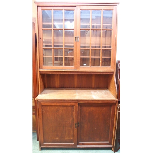 69 - A 20th century pine kitchen cabinet with glazed sliding doors over open compartment over sliding pan... 