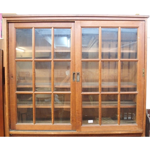 69 - A 20th century pine kitchen cabinet with glazed sliding doors over open compartment over sliding pan... 