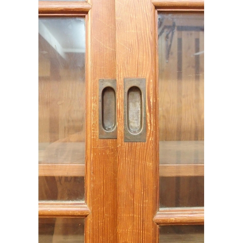 69 - A 20th century pine kitchen cabinet with glazed sliding doors over open compartment over sliding pan... 