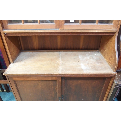 69 - A 20th century pine kitchen cabinet with glazed sliding doors over open compartment over sliding pan... 