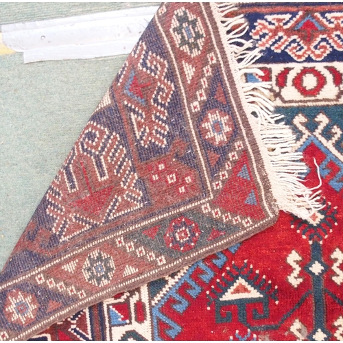 94 - A red ground Balouch rug with geometric central panel and dark blue borders