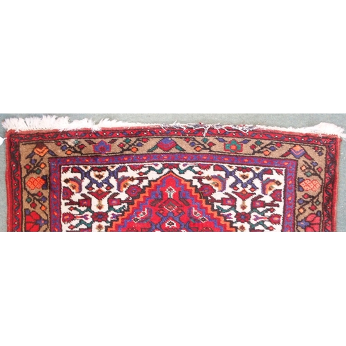 95 - A red ground Balouch rug with geometric central panel and beige border