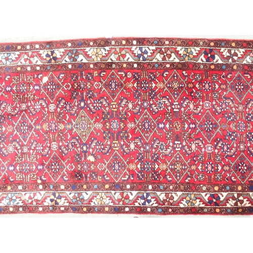 96 - A red ground Persian runner with all over geometric design, white spandrels and a multicoloured flow... 