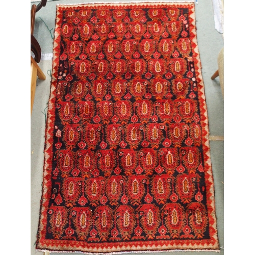 61 - A dark ground hand woven eastern rug with all over lozenge design, 186cm long x 111cm wide