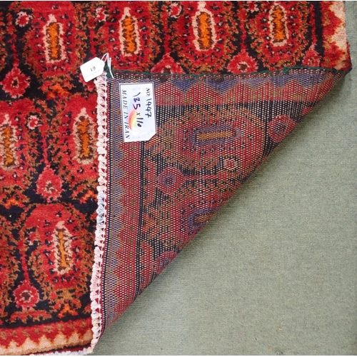 61 - A dark ground hand woven eastern rug with all over lozenge design, 186cm long x 111cm wide