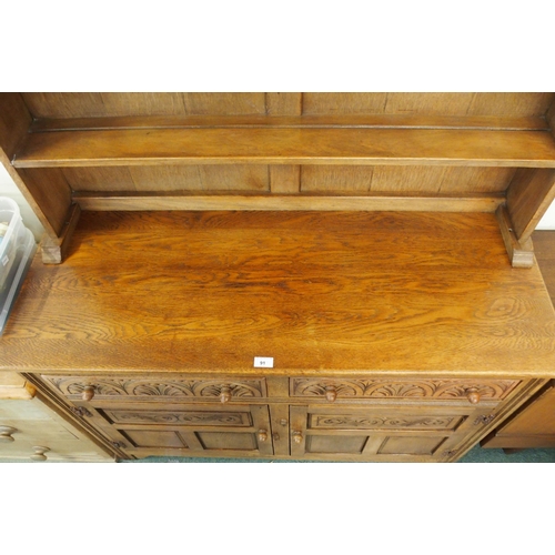 91 - A 20th century oak kitchen dresser with dome topped plate rack over two drawers over two cabinet doo... 