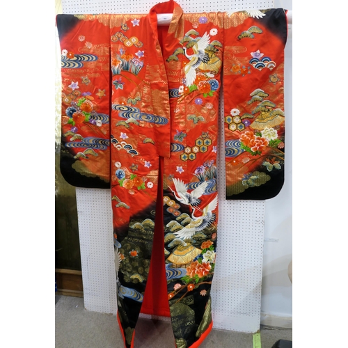 164 - A modern Japanese marriage ceremonial kimono with embroidered decoration on a red and black silk gro... 