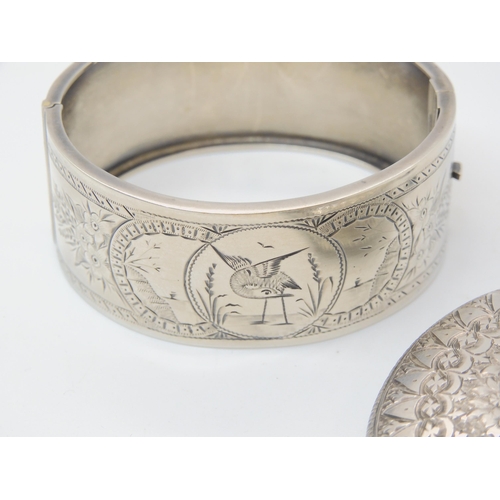 684B - A silver bangle engraved with a bird, and a white metal Victorian heavily engraved locket