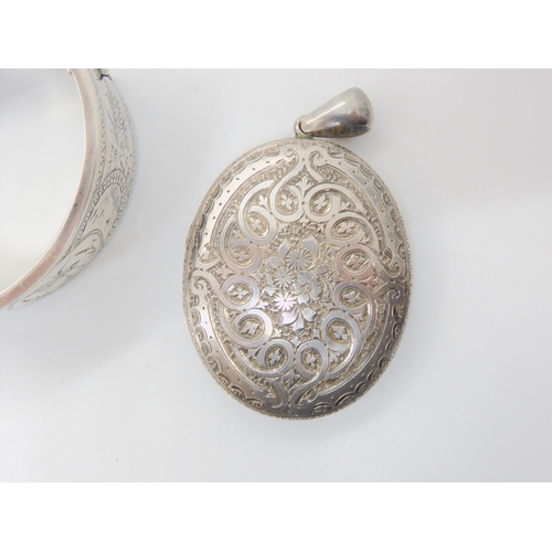 684B - A silver bangle engraved with a bird, and a white metal Victorian heavily engraved locket