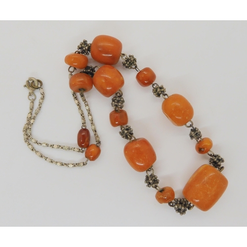 689 - A necklace of amber coloured beads with a white metal decorative chain, weight 21.5gms