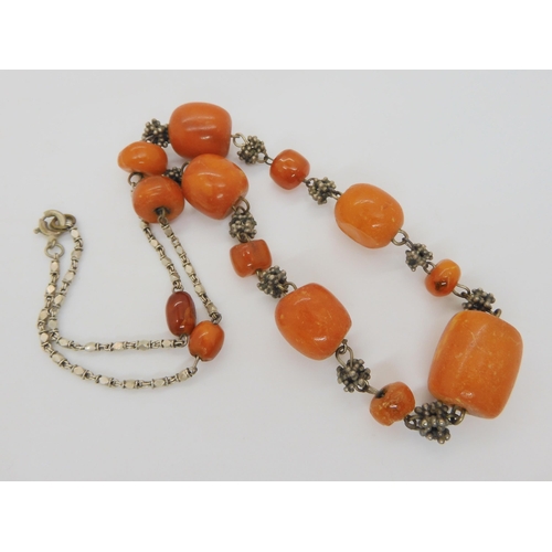 689 - A necklace of amber coloured beads with a white metal decorative chain, weight 21.5gms