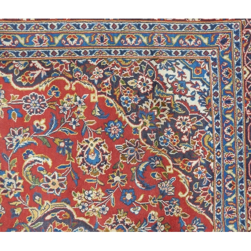 2142 - A RED GROUND KESHAN RUGwith all over floral foliate design, dark blue central medallion, matching sp... 