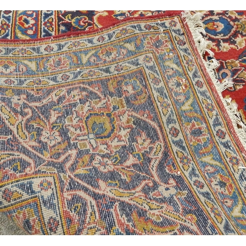 2142 - A RED GROUND KESHAN RUGwith all over floral foliate design, dark blue central medallion, matching sp... 